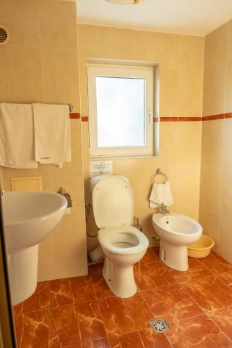 a bathroom with a toilet and a sink and a window at Family Hotel Mimosa in Tsarevo