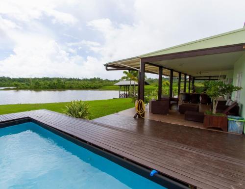a villa with a swimming pool and a house at Appartement Ecovilla Blauwmeer in Paranam