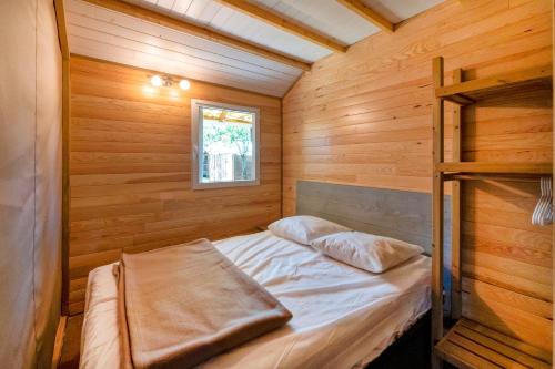 a bedroom with a bed in a wooden cabin at Lodge 4 - Domaine Des Landes in Lesperon