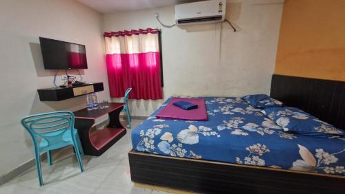 a bedroom with a bed and a desk and a television at Aditya Inn in Gopālpur