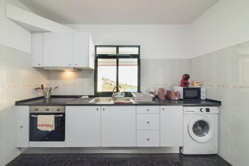a kitchen with white cabinets and a washing machine at Casa do Vale by Mth in Ribeira Brava
