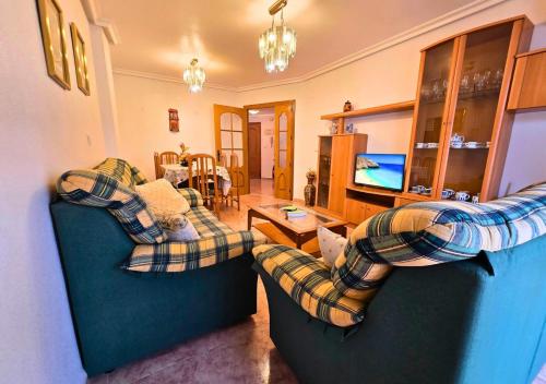 Una sala de estar con dos sofás y un televisor. en Apartamento Las Olas Santa Pola, en Santa Pola