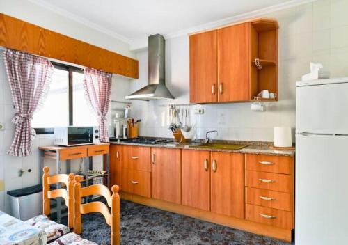 a kitchen with wooden cabinets and a white refrigerator at Apartamento Parque Reina Sofía in Guardamar del Segura
