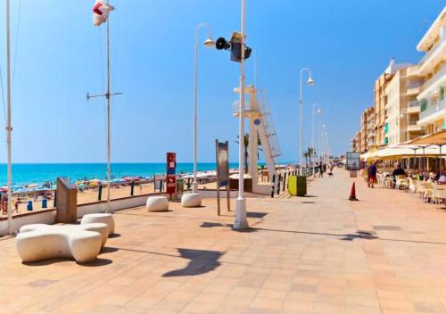a boardwalk on a beach with the ocean and buildings at Apartamento Parque Reina Sofía in Guardamar del Segura