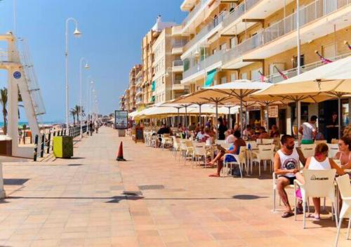 a group of people sitting in chairs on a sidewalk at Apartamento Parque Reina Sofía in Guardamar del Segura