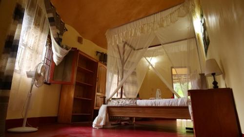 a bedroom with a canopy bed with a window at Vijiji Center Lodge and Safari in Arusha