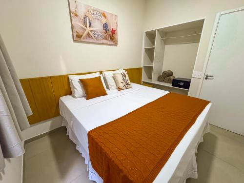 a bedroom with a large white bed with an orange blanket at Hotel Nacional Inn Guarujá in Guarujá