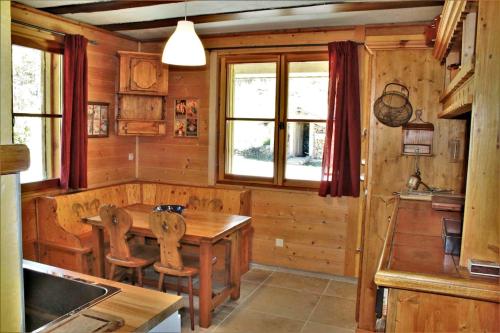 a kitchen with a wooden table and chairs and windows at L'Evasion Authentique - Nature & Cheminée in Les Thuiles