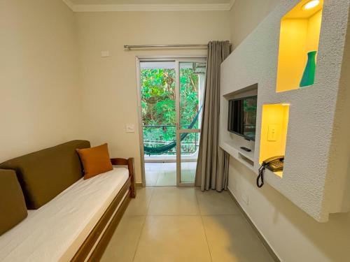 a living room with a couch and a tv at Hotel Nacional Inn Guarujá in Guarujá