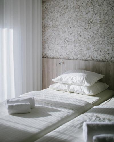 a bed with white sheets and pillows in a room at Hotel Capris Capodistria Boutique in Koper