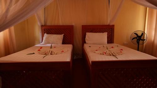 two beds in a room with flowers on them at Vijiji Center Lodge and Safari in Arusha