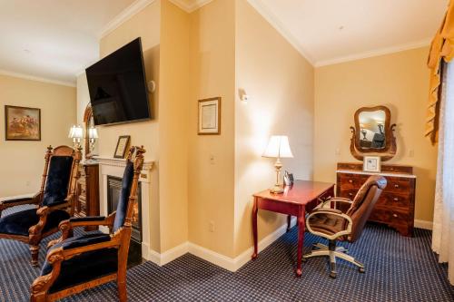 a hotel room with a desk and a table and chairs at Best Western White House Inn in Bangor