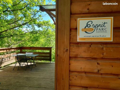 a sign on the side of a cabin with a table on a deck at Mon chalet au cœur des Cévennes in Vébron