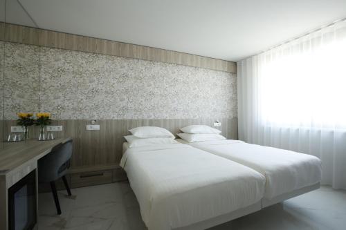 a hotel room with two beds and a desk and a desk at Hotel Capris Capodistria Boutique in Koper
