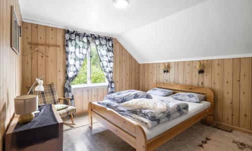 a bedroom with a bed with wooden walls and a window at Hundevennlig feriehus ved sjøen på Geisnes in Sørmoen