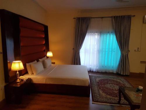 a bedroom with a large bed and a window at Peace Palace Islamabad in Islamabad