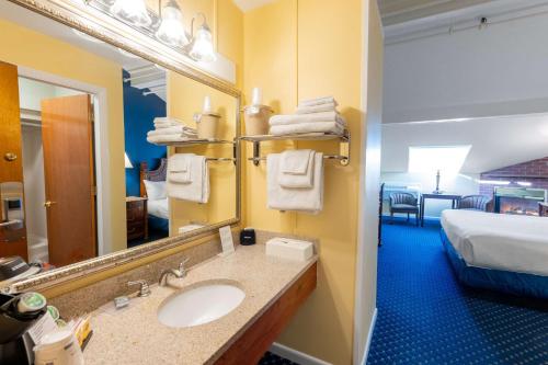 a bathroom with a sink and a mirror and a bed at Best Western White House Inn in Bangor