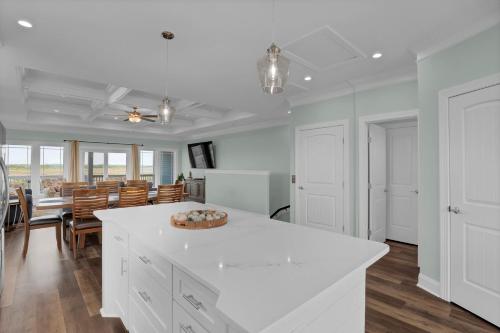 a kitchen and dining room with white cabinets and a table at 6 Bedrooms, New Construction, Ocean and Sound Views in North Topsail Beach