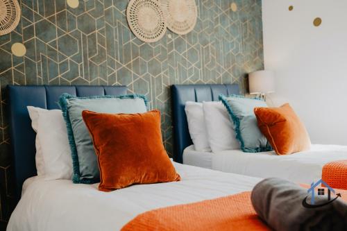 two beds with orange and blue pillows in a room at 4 Clovelly Court, Derby, DE22 1GS in Derby