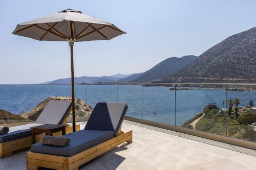 a patio with two chairs and an umbrella and the water at Celeste Bali Suites in Balíon