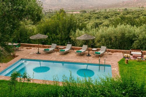 a swimming pool with lounge chairs and umbrellas next to at Atlas Smile Retreat in Ouirgane