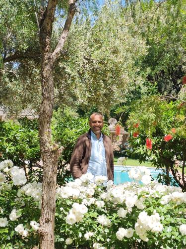 a man standing in a garden with white flowers at Atlas Smile Retreat in Ouirgane