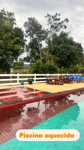 a swimming pool with tables and chairs in the water at Pousada Ibiza in Pirenópolis