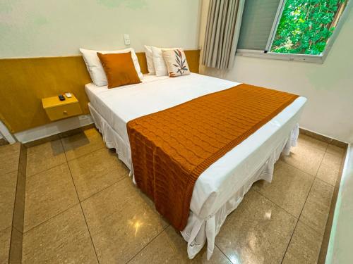 a bedroom with a large bed with an orange blanket at Hotel Nacional Inn Guarujá in Guarujá