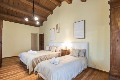 two beds in a room with white walls and wooden floors at Villa Le 12 Querce in Castel di Mezzo