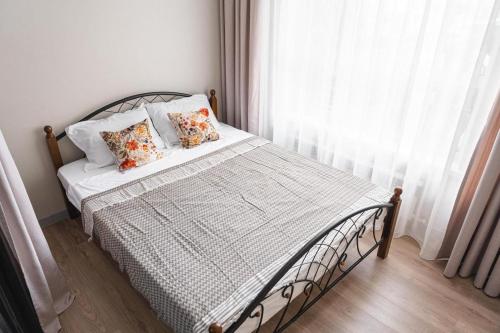 a bedroom with a bed with pillows and a window at Aqzam in Zhezdi