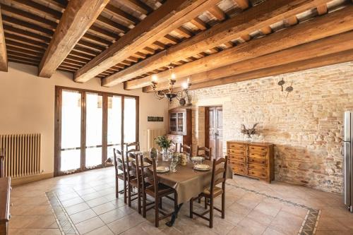 a dining room with a table and chairs and a brick wall at Villa Le 12 Querce in Castel di Mezzo