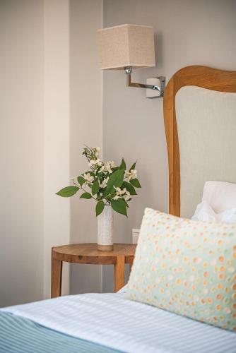 a vase of flowers on a table next to a bed at Ikion Eco Boutique Hotel in Patitiri