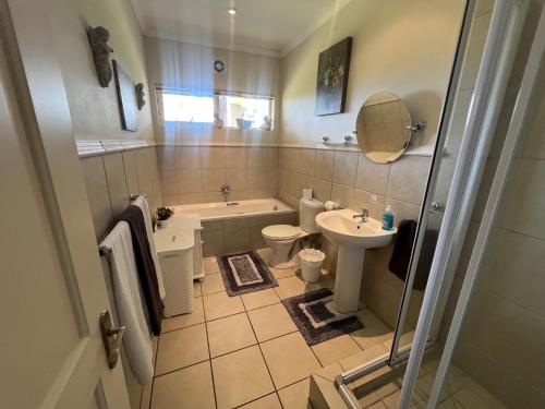 a bathroom with a tub toilet and a sink at Golfers paradise on 25th green in Hermanus