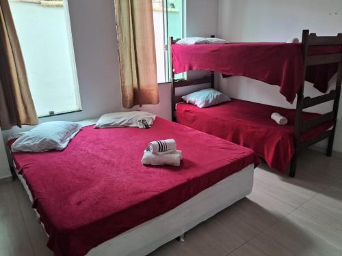 a bedroom with two bunk beds with red sheets at Pousada Ebenézer, Foguete in Cabo Frio