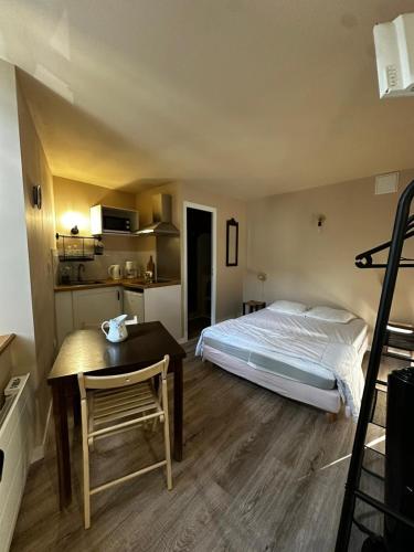 a bedroom with a bed and a table and a kitchen at Studio 5 Aux volets bleus in Aulus-les-Bains