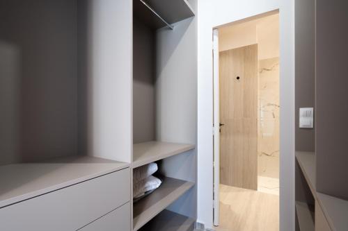 ein begehbarer Kleiderschrank mit weißen Schränken und einer Glastür in der Unterkunft RoomsByRamez -Chill Bright Stay- -Central Athens- in Athen