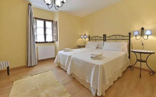 a bedroom with a large white bed and a window at Puente del Narcea 3 in Cibuyo