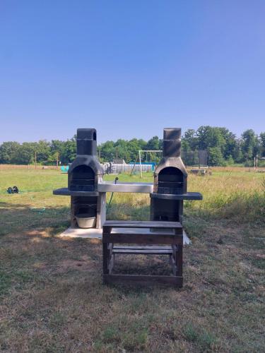 a grill in a field with a playground in the background at Comme chez Moi - Mobile-home dans camping à la ferme in Arcomps