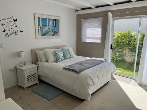 a bedroom with a bed and a large window at Golfers paradise on 25th green in Hermanus