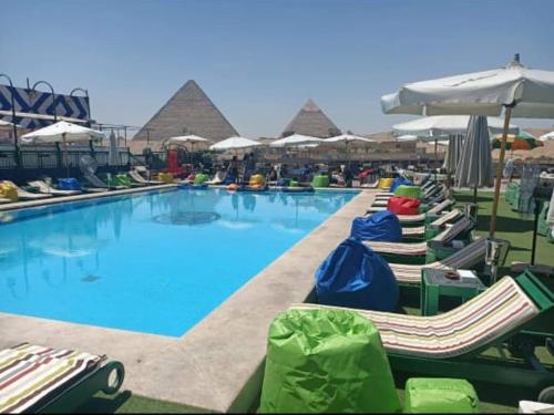 ROOF PYRAMIDS View في القاهرة: حمام سباحة مع كراسي استلقاء ومظلات