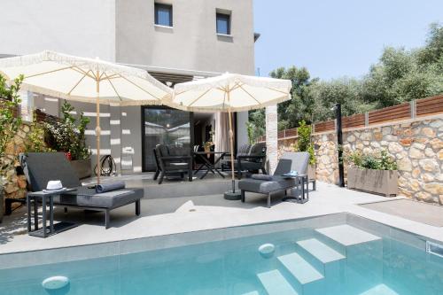 a patio with chairs and umbrellas next to a pool at September15 Suites- Meganisi in Meganisi