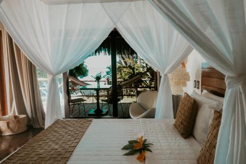 a bedroom with a bed with curtains and a balcony at Madeiro Beach Hotel in Pipa