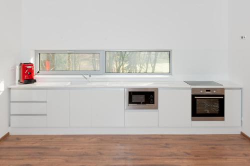 a white kitchen with a sink and two windows at Villa Ľadoveň LUXUSNÝ APARTMÁN 124m2 in Martin