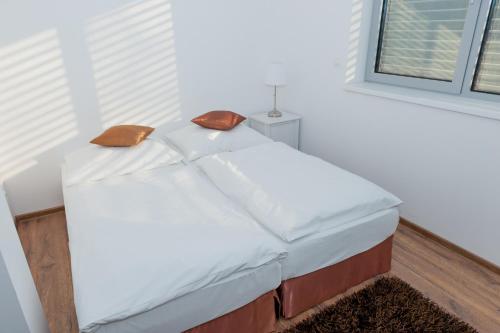 a white bed with two brown pillows on it at Villa Ľadoveň LUXUSNÝ APARTMÁN 124m2 in Martin
