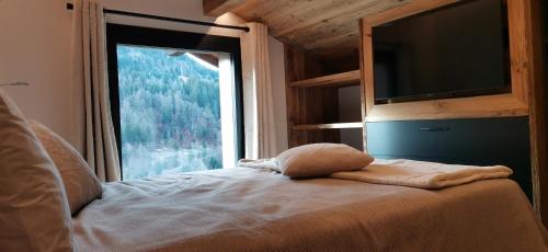 une chambre avec un lit avec une grande fenêtre dans l'établissement Appartement 3 chambres lumineux avec extérieur, à La Clusaz