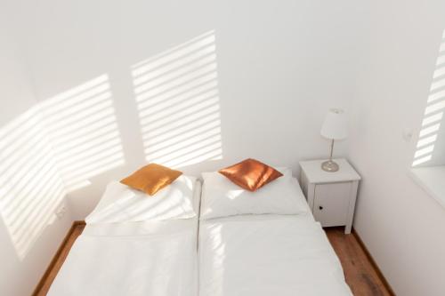 a white bed with two brown pillows on it at Villa Ľadoveň LUXUSNÝ APARTMÁN 124m2 in Martin