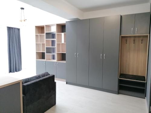 a kitchen with gray cabinets and a black couch at гест хаус паркова 33 in Razgrad