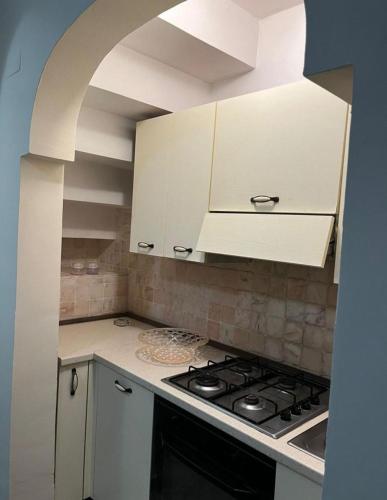 a kitchen with white cabinets and a stove top oven at Il nido in Alezio
