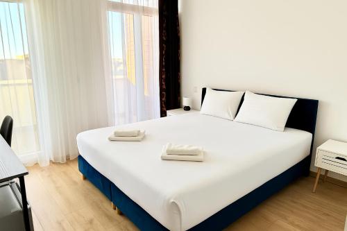 a bedroom with a large white bed with two towels on it at Rooftop City Residence with Underground Parking in Budapest