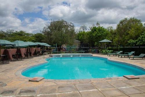 a large swimming pool with chairs and a table at Fountain Brook Gardens & Resort in Thika